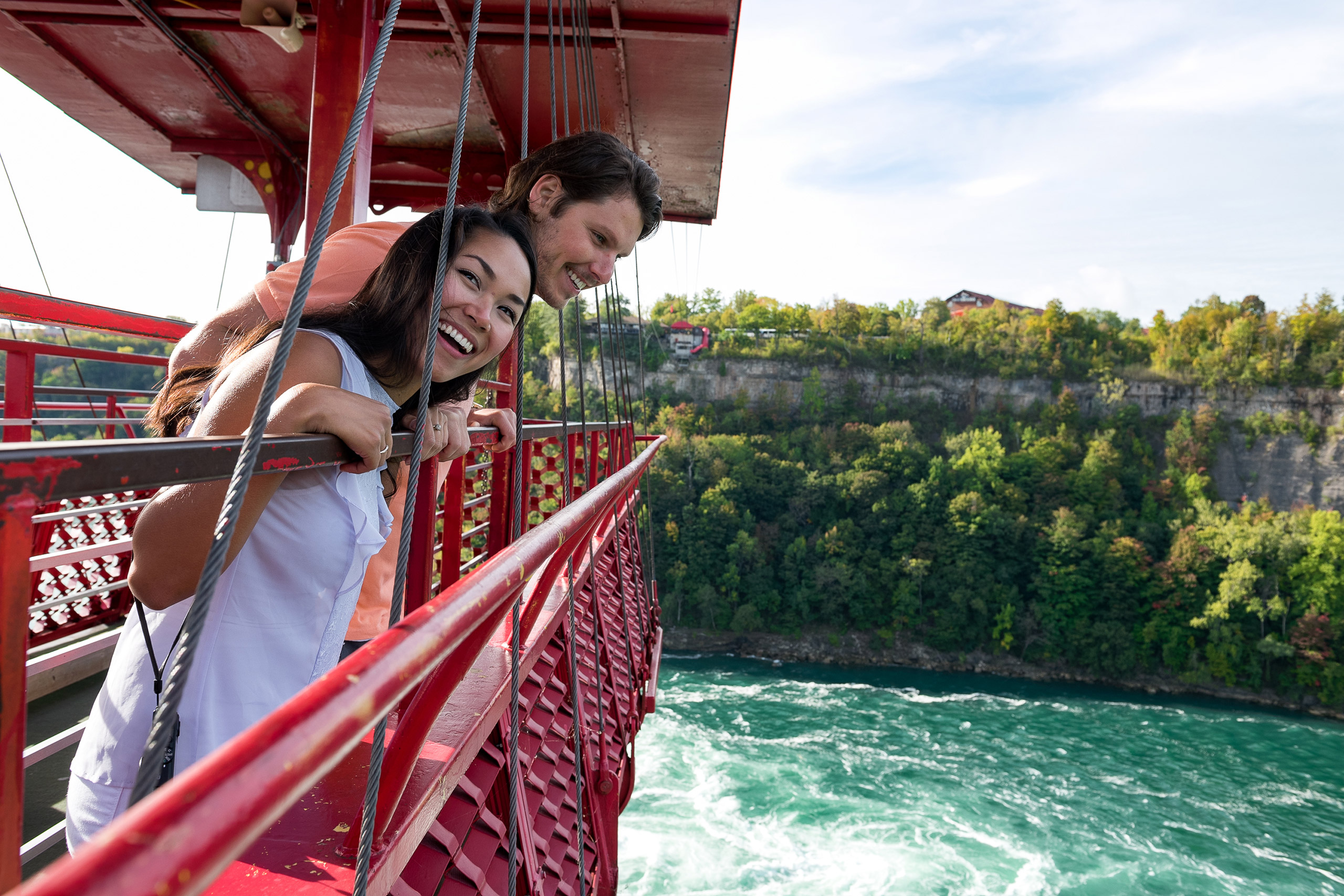 man and woman riding on cable car over water