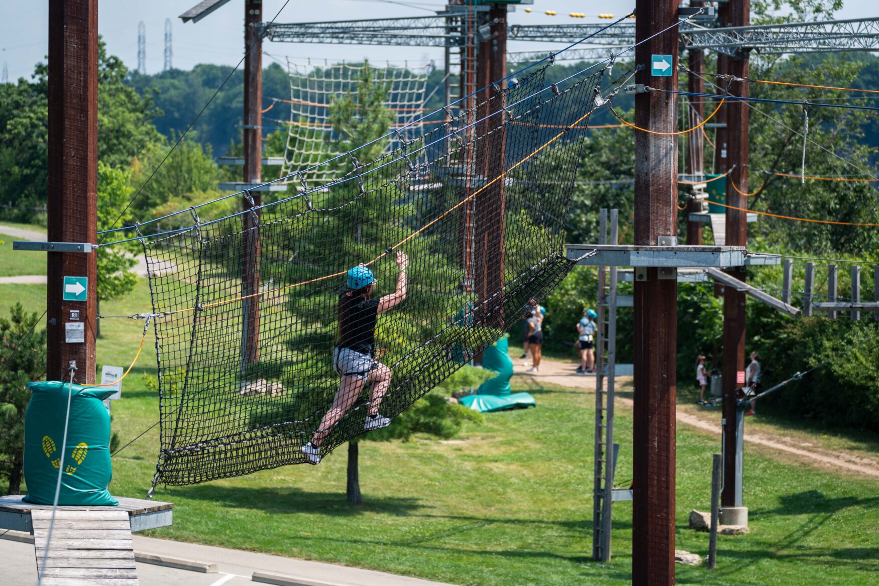A woman climbing through a net that connects 2 platforms