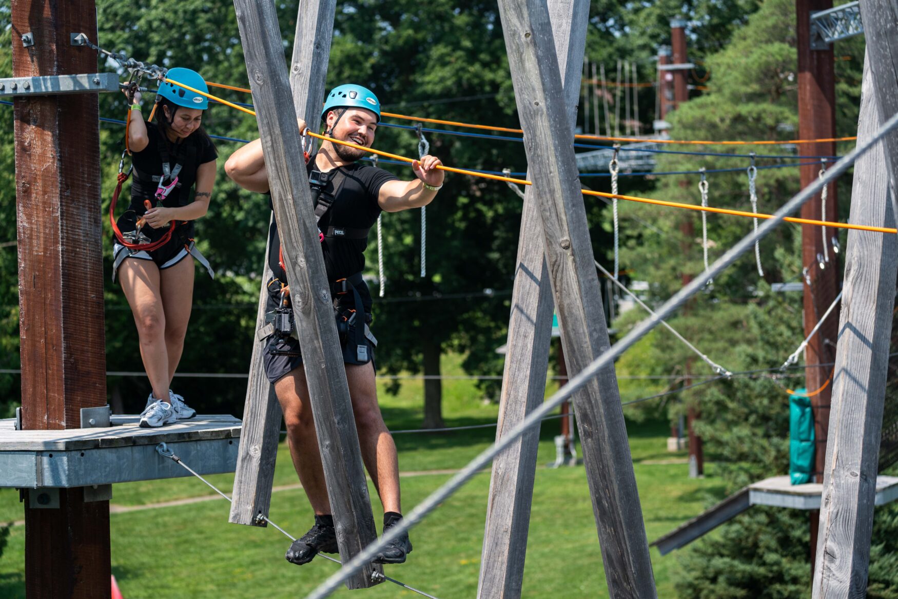 A man holding onto a wire and moving through wood beam obstacles