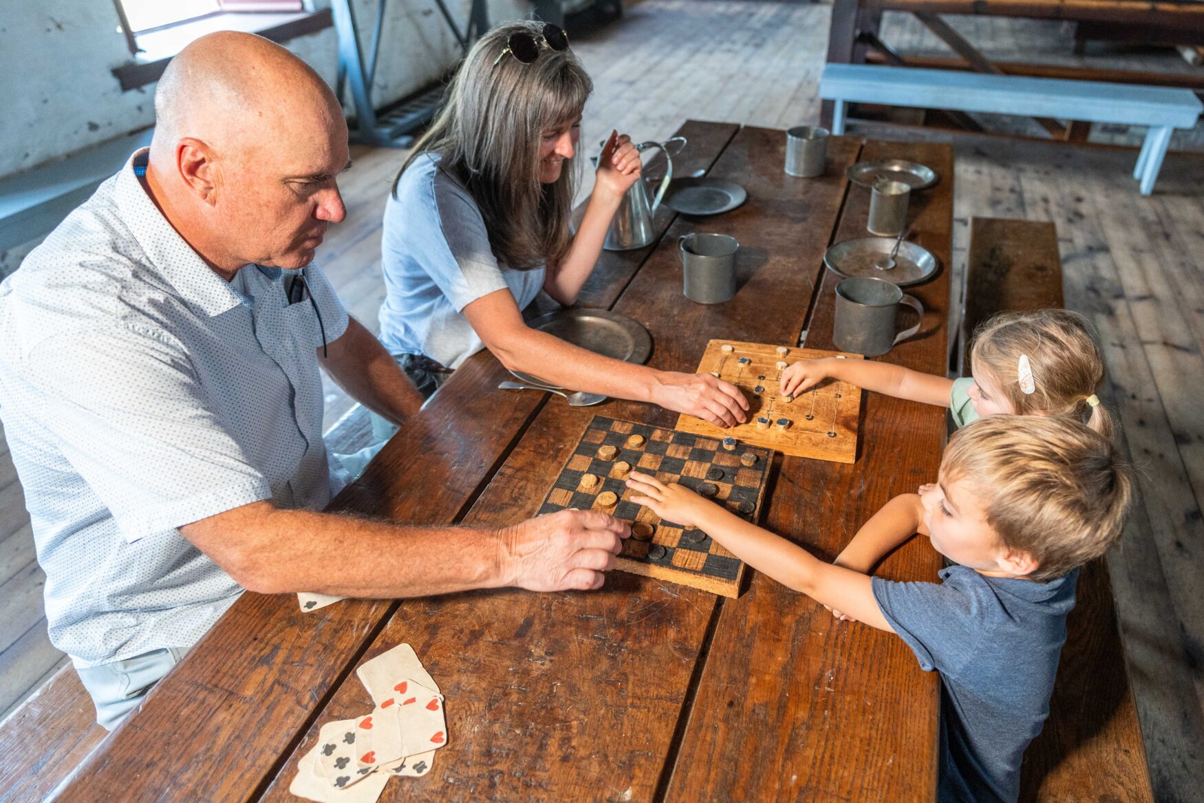 A boy and a man play checkers on a old board